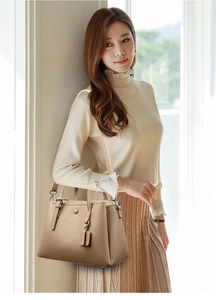 Chic beige pebble grain tote bag styled by model in a soft minimalist indoor setting