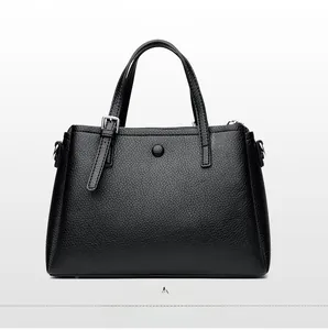 Detail view of the back of a black litchi pattern leather tote bag with snap button