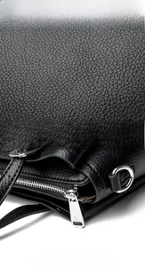 Macro shot of black lychee grain leather texture and TY engraved silver metal zipper
