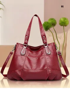 Macro detail of wine red quilted faux leather texture on large tote bag with silver hardware