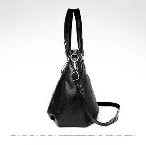 Detailed side view of black textured leather tote with silver hardware and shoulder strap