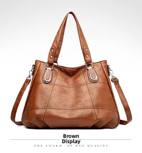 Close-up of yellow-brown PU leather tote bag with cross stitching and silver metal rivets