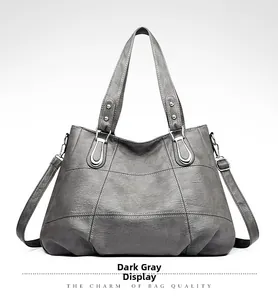 Detailed close-up of dark grey crossbody bag showing faux leather texture and metallic buckles
