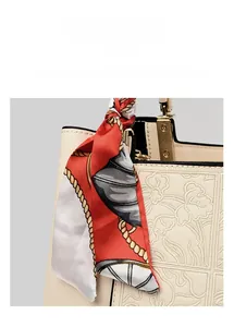 Detail of embroidered tote bag with cream embossed texture, silk ribbon and gold hardware