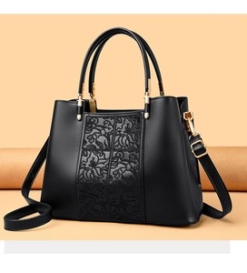 Detail of floral embossed texture on black leather tote bag with gold hardware