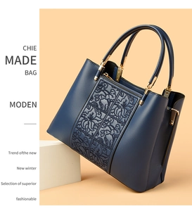 Close-up of elegant navy leather handbag with floral relief and gold metal hardware