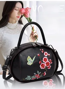 Detail of vintage black leather bag with floral embroidery and adjustable strap