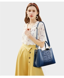 Detailed view of dark blue structured handbag with floral embossing and gold hardware