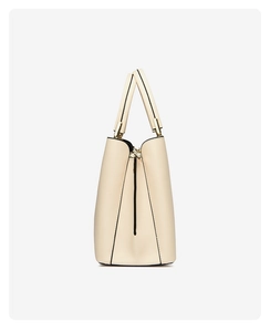 Side view detail of cream embroidered handbag showing neat black oil edges and gold hardware