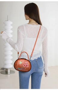 Detail of vintage brown bag with flower and butterfly embroidery on a white lace outfit