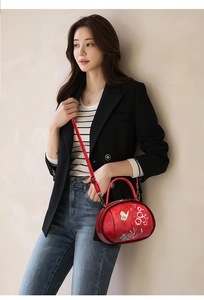 Detail of red vintage bag with flower and butterfly embroidery worn by a model