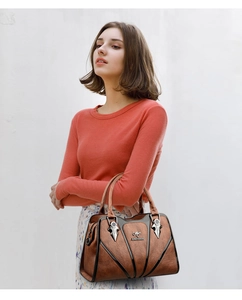 Close-up of brown structured tote bag with metallic logo and elegant black trim detailing