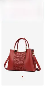 Detailed close-up of red elegant embroidered handbag with golden hardware accents