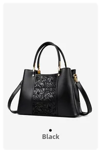 Detail of black embroidered handbag featuring floral relief patterns and gold hardware