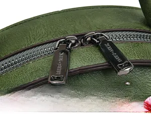 Detailed macro view of dark forest green leather bag with floral embroidery and metal zipper