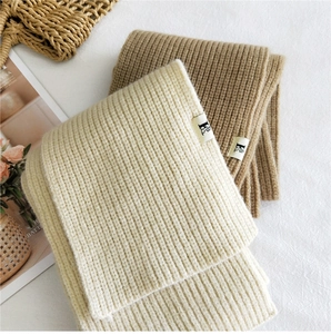 Detailed texture of thick ribbed knit scarves in beige and camel with brand woven labels