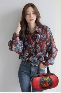 Close-up of red leather handbag with vibrant floral embossing and retro floral blouse