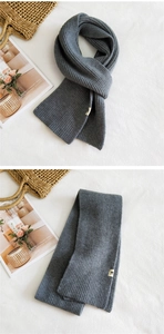 Detailed view of dark grey thick rib-knit scarf with soft texture and white brand label