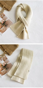 Close-up of beige chunky knit scarf featuring a minimalist black fabric logo label