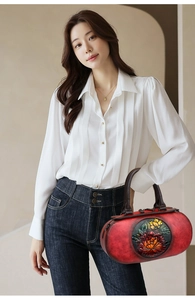 Detail of vintage red cylinder handbag with 3D floral carving held by a model