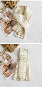 Dettaglio della trama a maglia della sciarpa beige a pois con finiture raffinate