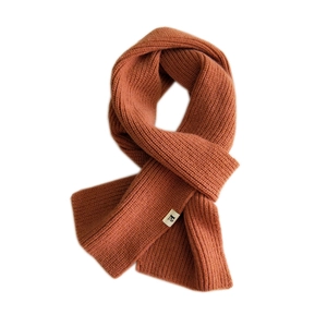 Thick orange knit scarf with rib pattern and small character label for winter warmth