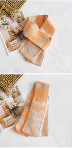 Dettaglio della sciarpa in maglia double-face con pois arancioni e motivo pied-de-poule