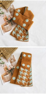 Dettaglio di una sciarpa in maglia arancione vivace con pois azzurri e motivo pied de poule