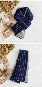 Dettaglio di sciarpa in maglia blu navy con pois grigi e consistenza soffice