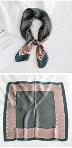 Détail d'un foulard en soie vert foncé et beige avec motifs géométriques et pliage