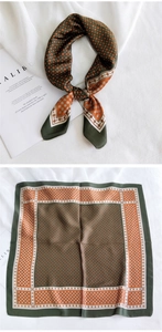Détail d'un carré de soie avec bordure vert foncé et motifs géométriques orange vif