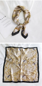 Détail d'un foulard en satin avec imprimé chaîne dorée et large bordure noire
