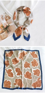 Gros plan d'un foulard carré en soie avec motif floral, bordures bleues et satiné