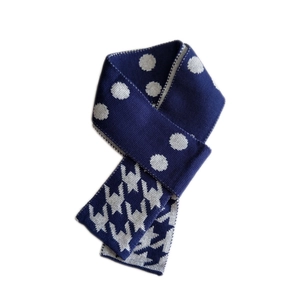 Sciarpa in maglia blu scuro e bianca con pois e motivo pied-de-poule su sfondo bianco