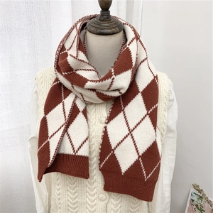 Dettaglio del motivo a rombi rosso e bianco su una sciarpa invernale in maglia da donna