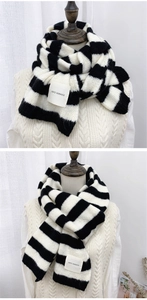 Close-up of black and white striped knitted scarf with thick weave and fabric label detail