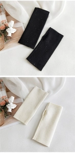 Detailed view of knitted fingerless arm warmers with thumb holes in black and beige