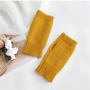 Close-up of ginger yellow knitted fingerless gloves with ribbed cuffs and thumb hole detail