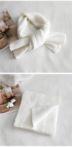 Detail of soft cream white ribbed knit scarf shown folded and tied for winter warmth