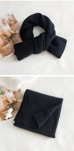 Close-up of thick black ribbed knit scarf texture with cozy winter accessories on a table