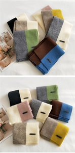 Detail of soft bicolored knitted scarves featuring an AMILE leather logo label patch