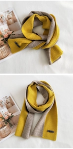 Detail of two-tone knit scarf in ginger and grey with a stitched logo and soft texture