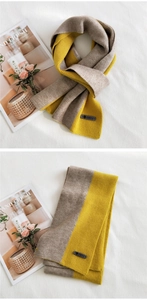 Close-up of knit scarf with leather tag detail in ginger yellow and light coffee contrast