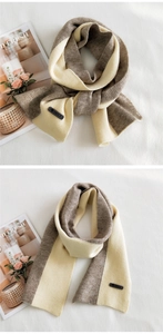 Detailed knit texture of two-tone scarf with AMILE brand leather patch on soft fabric