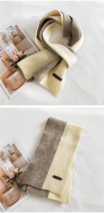 Detail view of thick knit scarf showing smiley face leather patch and two-tone color block