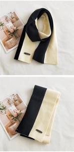 Detail of two-tone knit scarf with textured thick stripes and a decorative leather tag