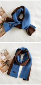 Detail of blue and brown knitted scarf with leather AMILE brand label on fabric