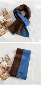 Close-up of dual-color knitted scarf texture with AMILE leather label and ribbed pattern
