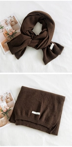 Macro shot of dark brown knitted scarf featuring ribbed edges and a minimalist woven label