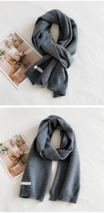 Detail view of dark grey ribbed knit scarf with a minimalist white woven brand label